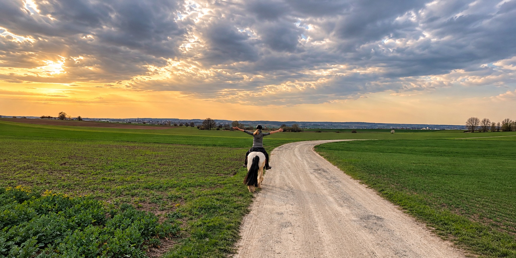 Ausritt auf einem Feldweg mit weit ausgebreiteten Armen